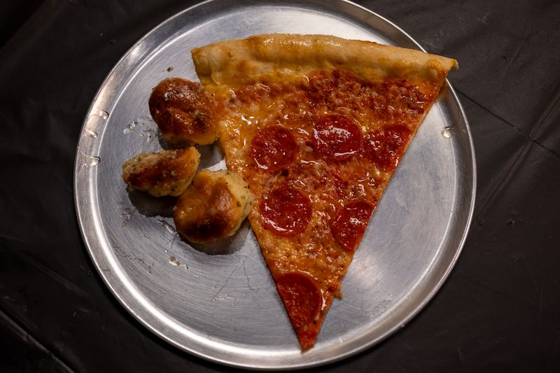 A pepperoni slice and three garlic knots on a metal pizza pan